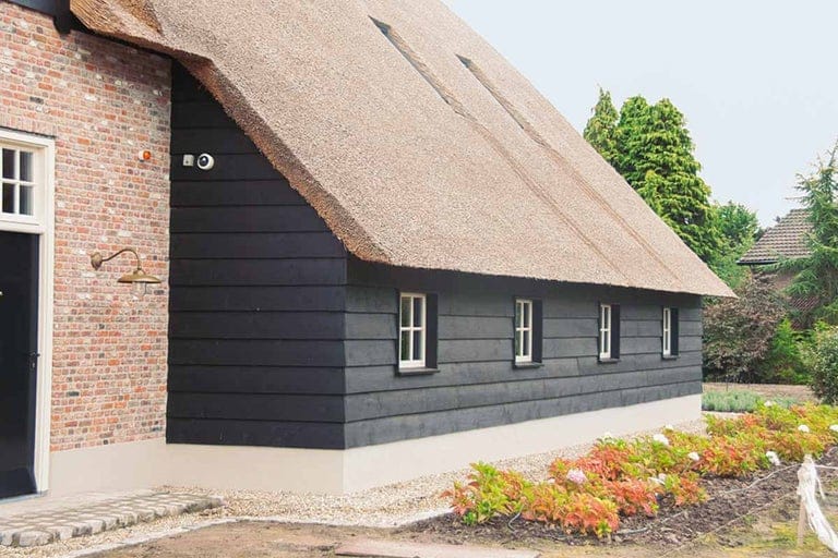 Zwarte houten potdeksel gevelbekleding aan een woning